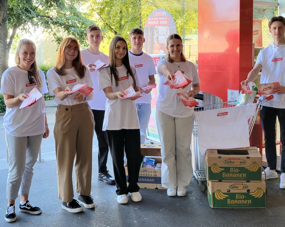 Lehrlinge in T-Shirts mit dem Print "Aktion Herz" halten Flyer der Aktion Herz in Richtung Kamera.