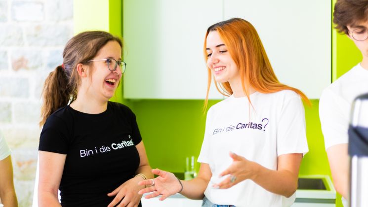 Zwei junge Frauen in T-Shirts mit der Aufschrift "Bin i die Caritas?"