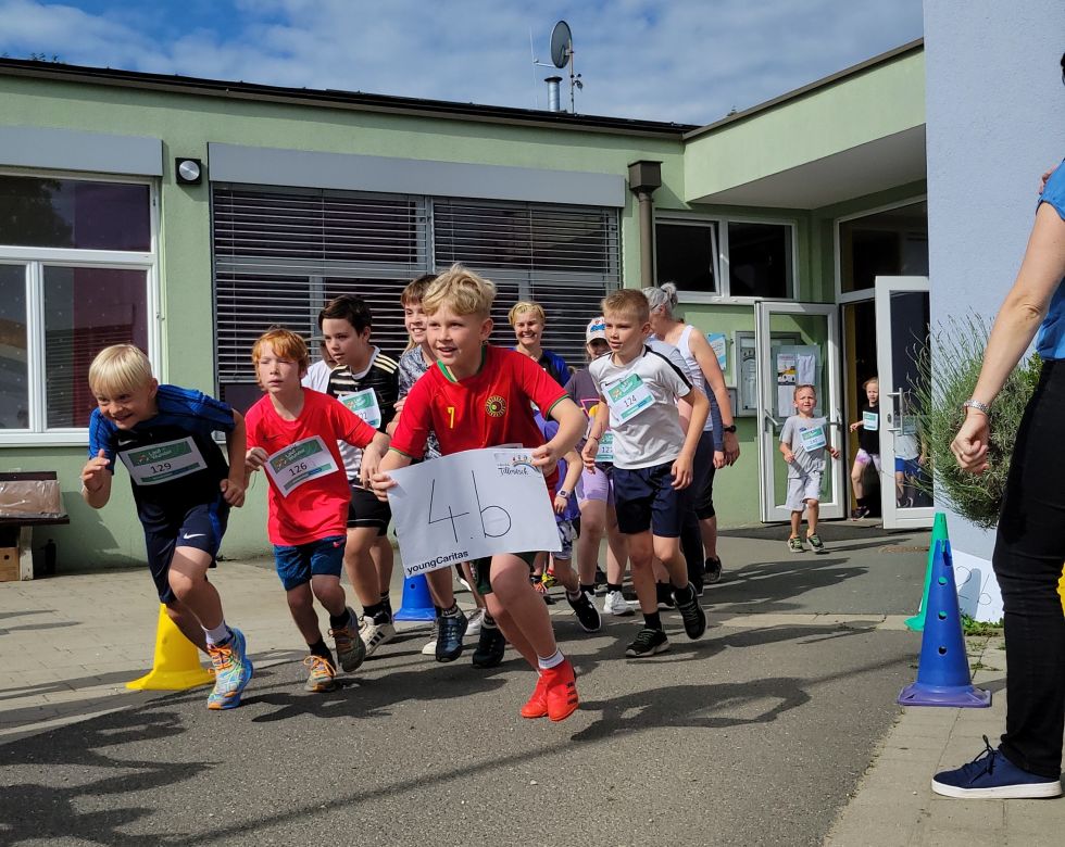 Schulkinder starten ihren Lauf. Der vorderste Läufer hält ein Schild mit der Aufschrift 4B.