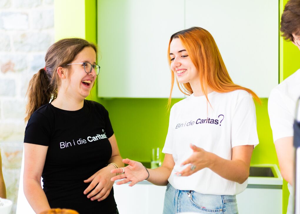 Zwei junge Frauen in T-Shirts mit der Aufschrift "Bin i die Caritas?"