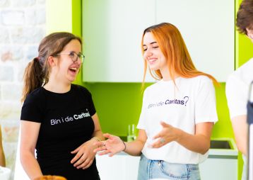 Zwei junge Frauen in T-Shirts mit der Aufschrift "Bin i die Caritas?"