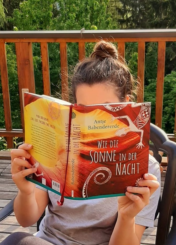 Mädchen liest ein Buch am Balkon