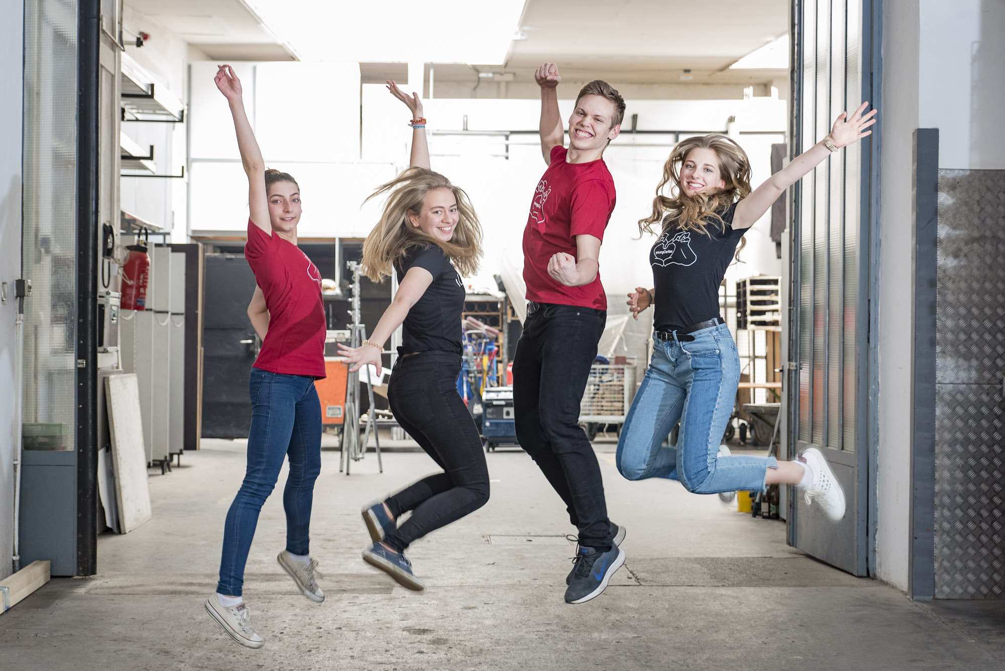 Junge Erwachsene springen und lächeln in die Kamera.